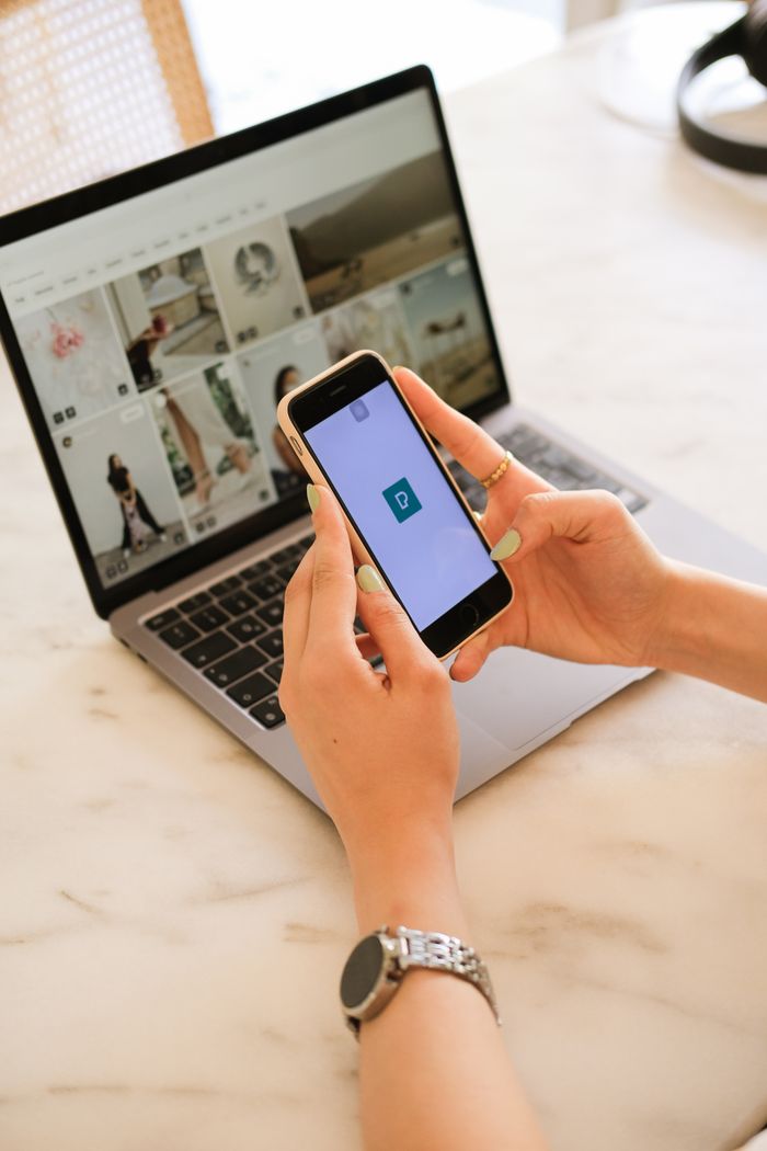 get-in-touch Close-up of a woman using smartphone and laptop, multitasking technology concept.