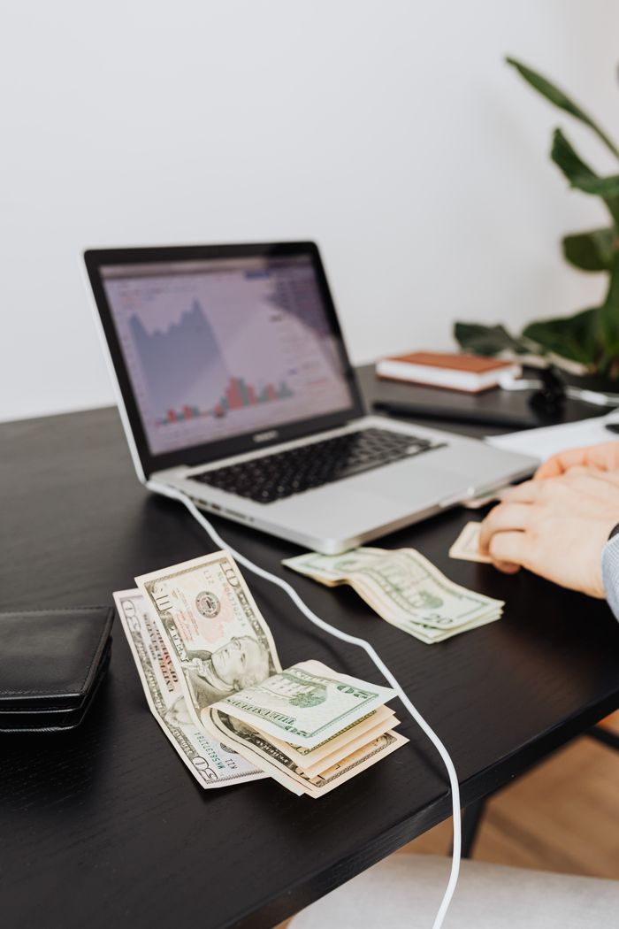 services-05 Money and laptop on desk indicating financial work or analysis. Perfect for business themes.