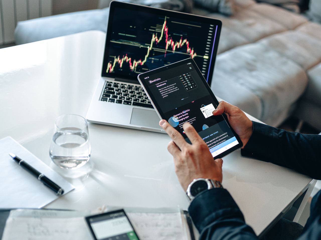 home-hero Person analyzing digital market trends on tablet with laptop showing financial charts.