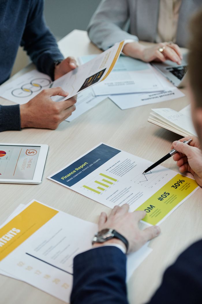 services-bg Professionals working together in an office, analyzing financial reports and documents with focus on graphs and teamwork.